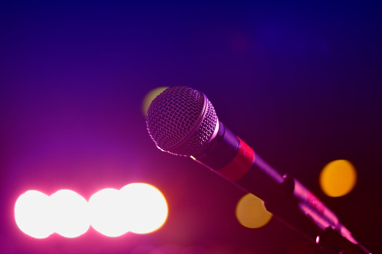 about-03 Colorful stage lighting highlights a microphone in a close-up view, perfect for music and performance themes.