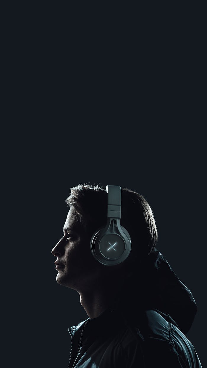 about-02 Moody portrait of a young man wearing headphones against a dark studio backdrop.
